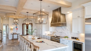 A spacious kitchen with a large island, modern appliances, and a high ceiling with exposed beams. - Sleeps 24, Elevator, Private Beach Boardwalk, Infinity Pool | 20 Bradley Circle (Hilton Head Island)