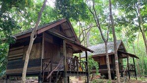 Zwei Holzhütten in einem Wald, jede mit einer Veranda und einer Treppe, die zum Eingang führt.