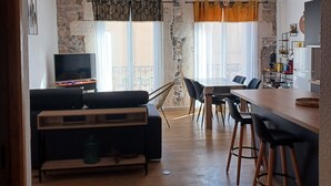 Ein modernes Wohnzimmer mit Sofa, Fernseher und Essbereich mit Stühlen und Tisch.