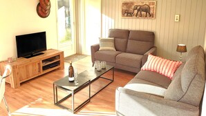 Una sala de estar con un sofá, una mesa de centro, un televisor y un aparador de madera.