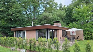 Una casa moderna con fachada de ladrillo, ventanas amplias y un patio con mobiliario exterior.