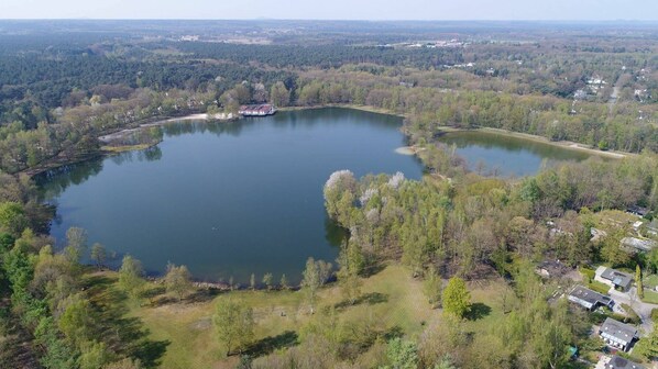 Une vue aérienne d’un lac entouré d’une forêt dense et de quelques bâtiments dispersés.