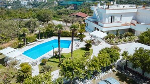 A modern villa with a swimming pool, lush greenery, and a view of a coastal town. - La Quiete, Exclusive Villa with private pool and Jacuzzi (Vico Equense)