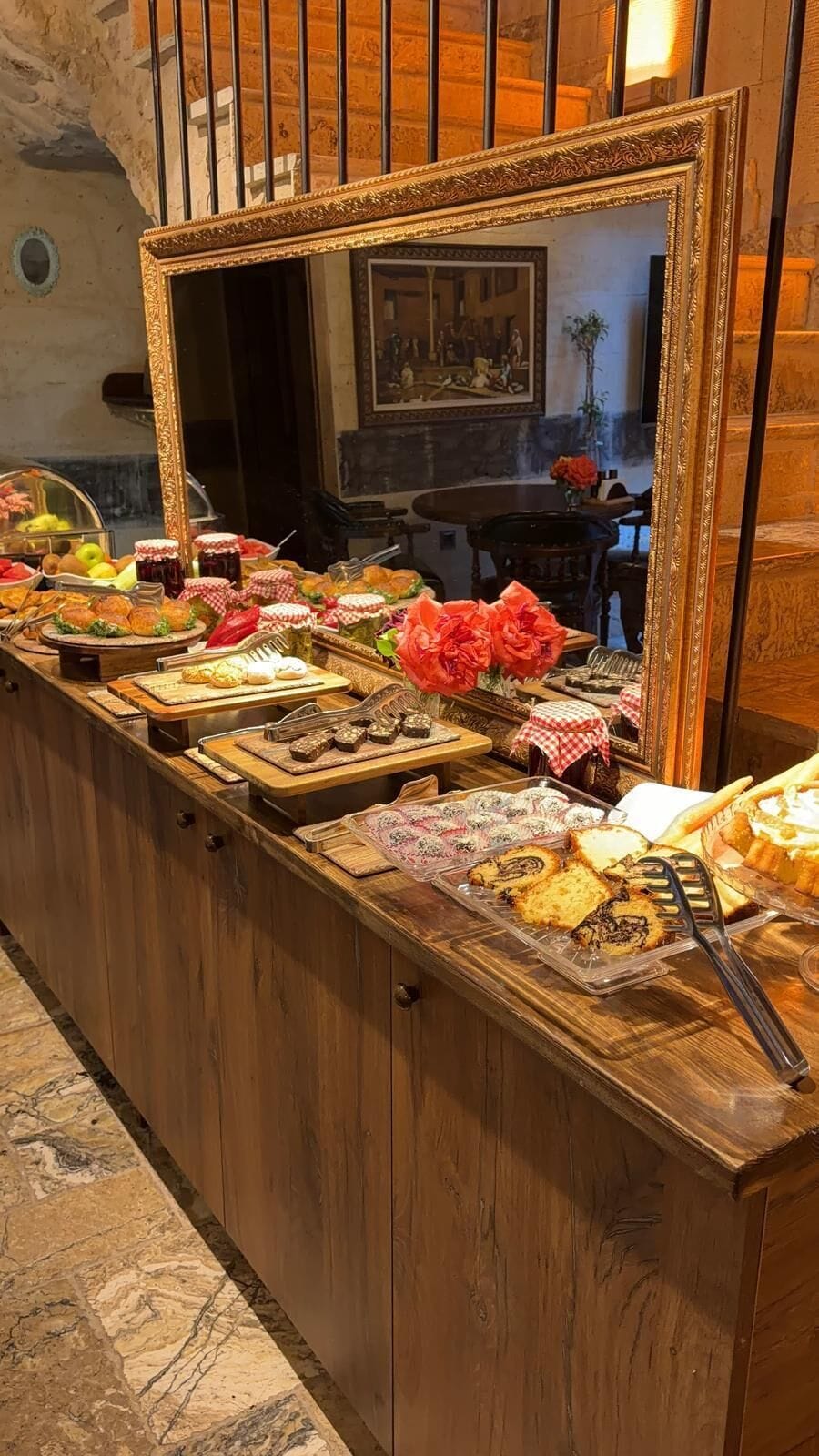 A buffet with various food items and a mirror reflecting the room's interior.