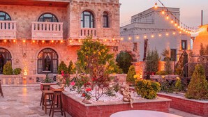 A courtyard with outdoor seating, a fountain, and string lights. - Cappadocia Chiaro (Nevsehir)