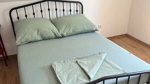 Ein Bett mit Metallgestell, zwei Kissen und einer gefalteten Decke.