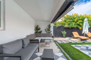 A modern outdoor living area with a gray sofa, a small table, and two lounge chairs.