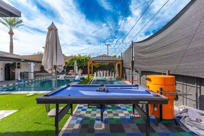 A pool table with a checkered tablecloth, a covered seating area, and a pool in the background. - 5ST Tranquil Escape in Vibrant Scottsdale (Scottsdale)