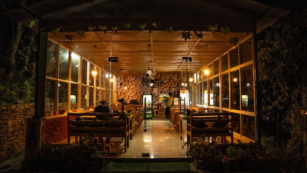 Un restaurant situé à l’intérieur, avec un long comptoir, des chaises et des tables en bois.