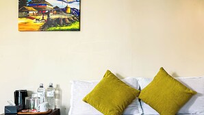 Une chambre d’hôtel avec un lit, deux oreillers verts, une table de chevet avec une lampe, un tableau au mur et un tissu décoratif vert sur le lit.