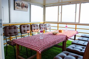 A dining area with a checkered tablecloth, leather chairs, and a painting on the wall.