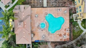 Vue aérienne d’un toit-terrasse aménagé avec une piscine, des chaises longues et un jacuzzi.