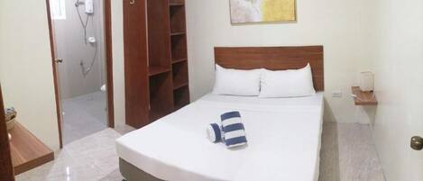 Habitación de hotel con cama, armario de madera, zona de ducha y un cuadro en la pared.