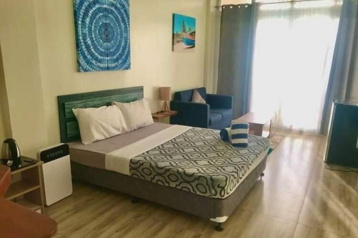 A hotel room with a bed, a chair, a desk, and a TV.