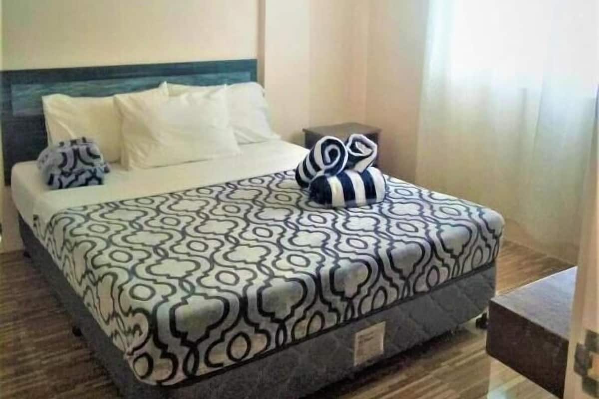 A bedroom with a bed, pillows, and a patterned bedspread.