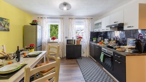 Eine kompakte Küche mit Essbereich, ausgestattet mit Kühlschrank, Mikrowelle, Herd und verschiedenen Küchengeräten.