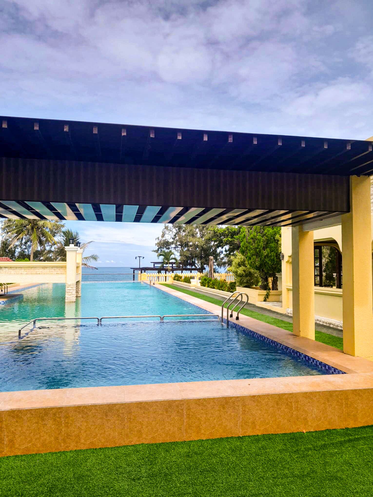 A swimming pool with a covered area and a view of the ocean.