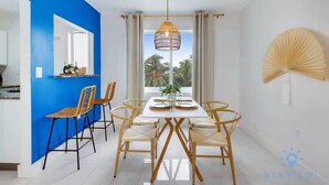 A dining area with a white table, six chairs, and a hanging light fixture. - Modern Beachside: Restaurants, Pool (Hollywood)