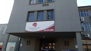 A building with a sign for Indaba Hotel in Sasolburg, featuring a contact number.