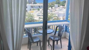 A balcony with two chairs and a table, overlooking a residential area and the sea. - Sunset view every night from your own balcony!

 (Paphos)