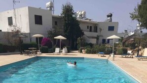 A rectangular swimming pool with clear blue water, surrounded by lounge chairs and umbrellas. - Sunset view every night from your own balcony!

 (Paphos)