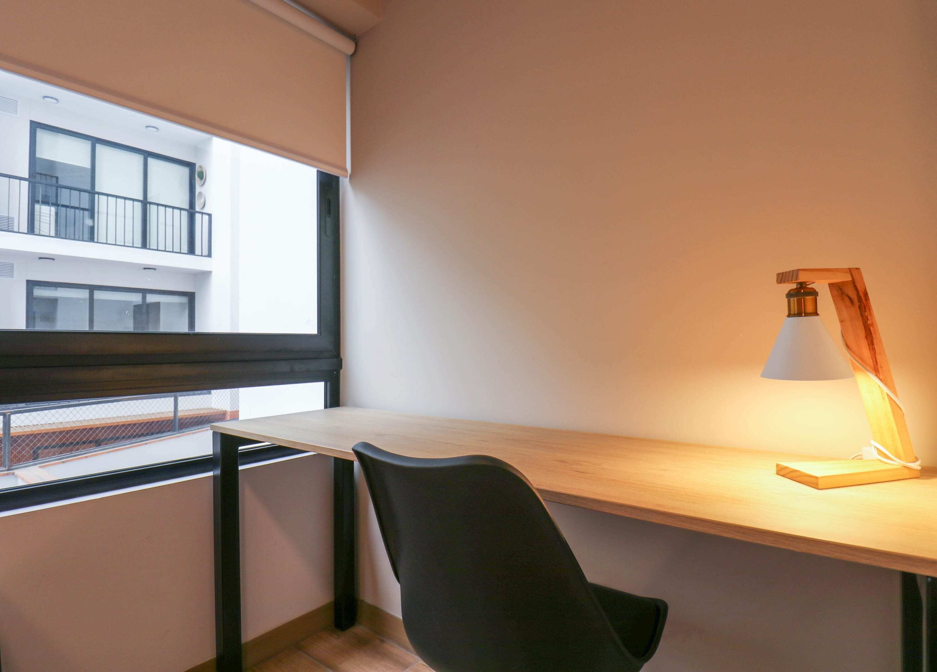 A modern office space with a desk, chair, and a lamp.