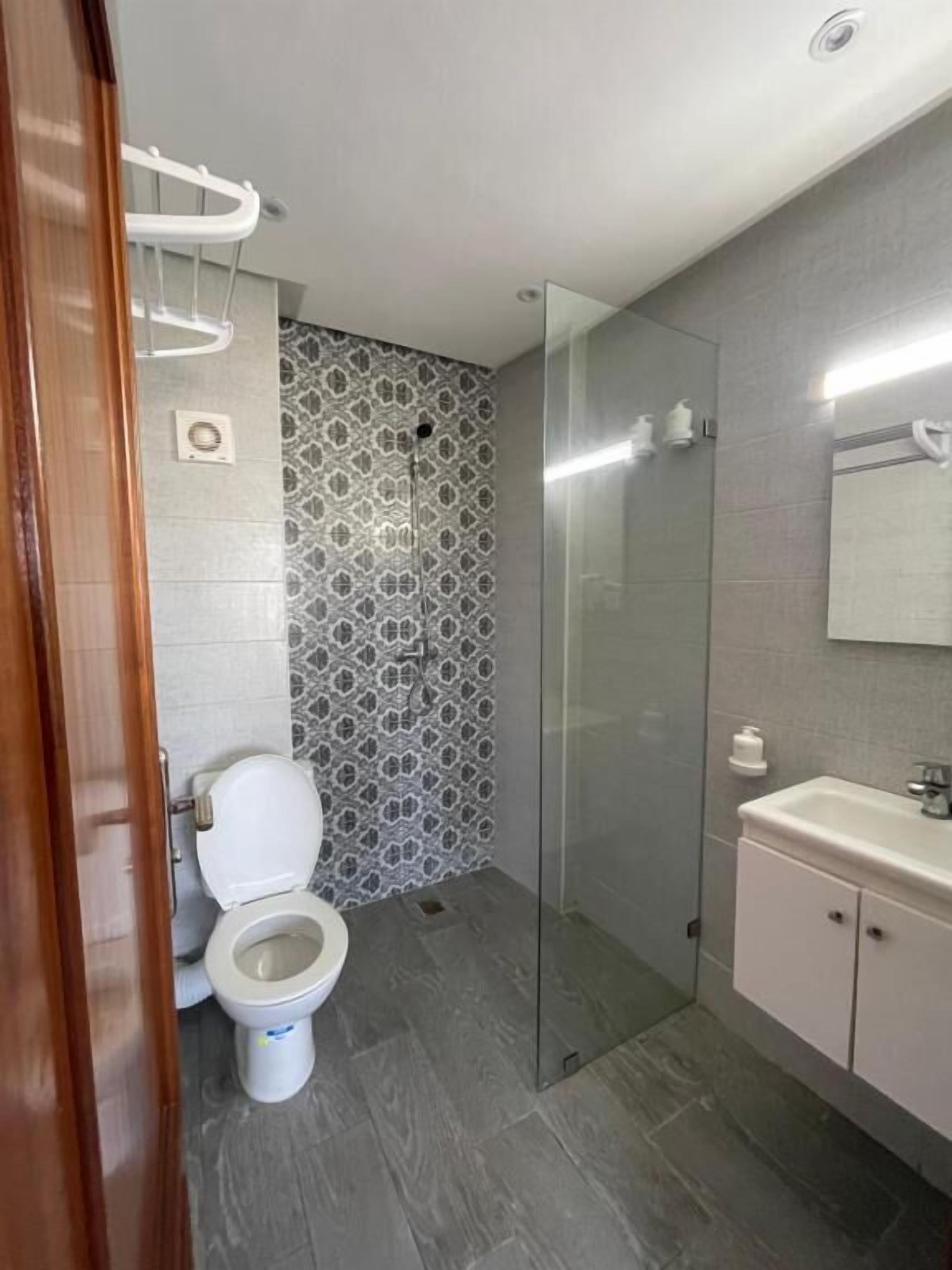 A bathroom with a toilet, a shower, and a sink.