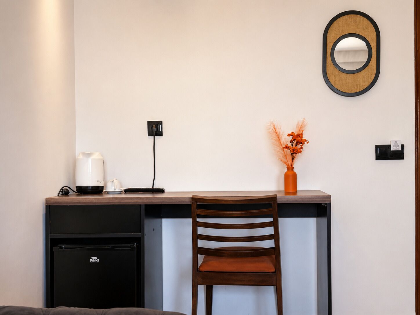A compact workspace with a desk, chair, and a small refrigerator.