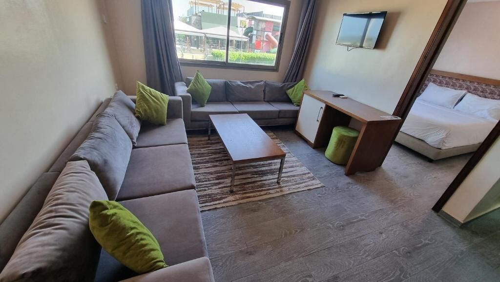 Una sala de estar con un sofá, una mesa de centro, un televisor montado en la pared y una cama.
