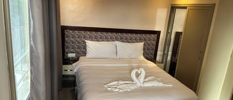 Habitación de hotel con una cama bien hecha, una mesita de noche con teléfono y un espejo en la pared.