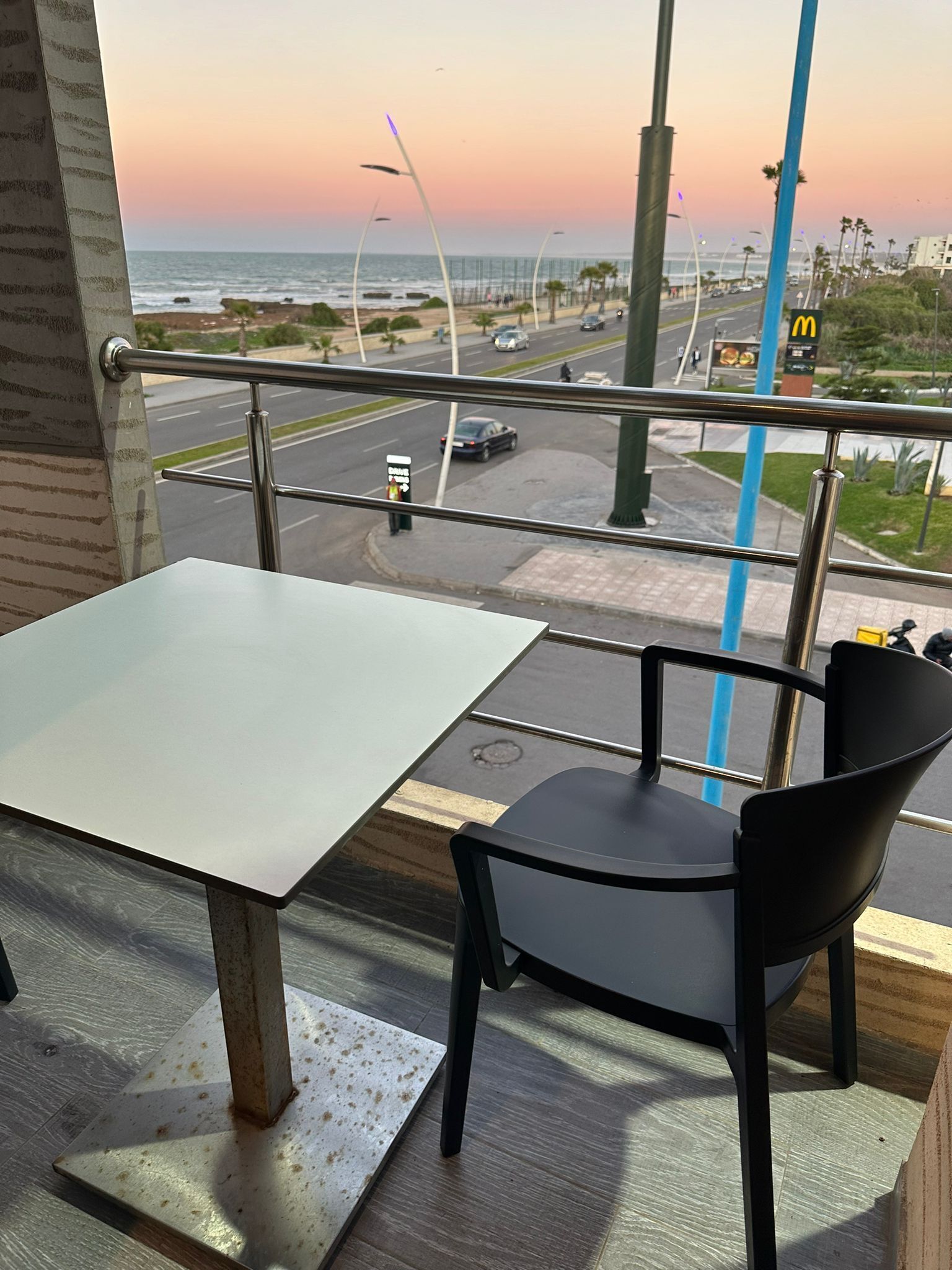 Un comedor con una mesa y sillas, vista a la calle y al océano, y un letrero de McDonald's.