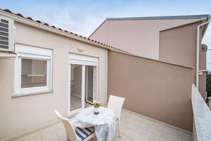 A small patio with a table and chairs, a sliding glass door, and a beige exterior wall. - Studio Apartments Near Center 3 (Novalja)