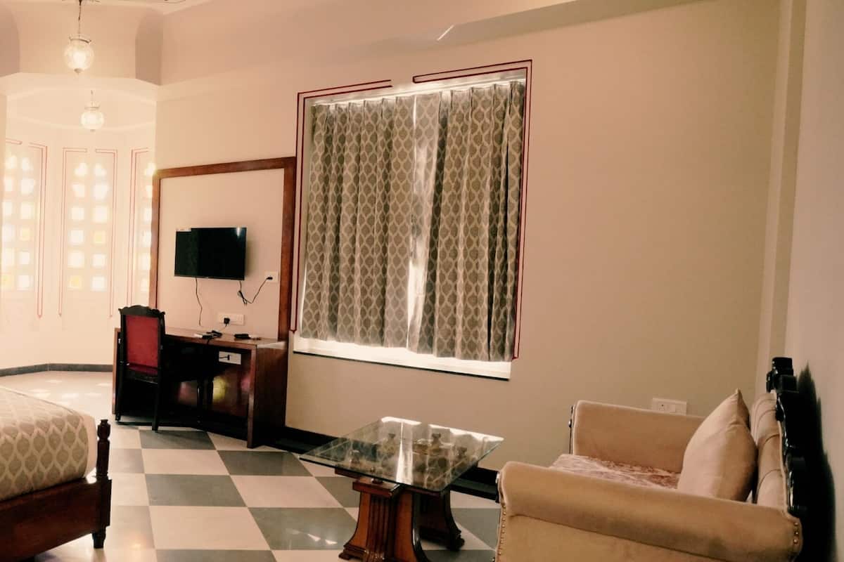A hotel room with a bed, a desk, a chair, a TV, and a window with curtains.