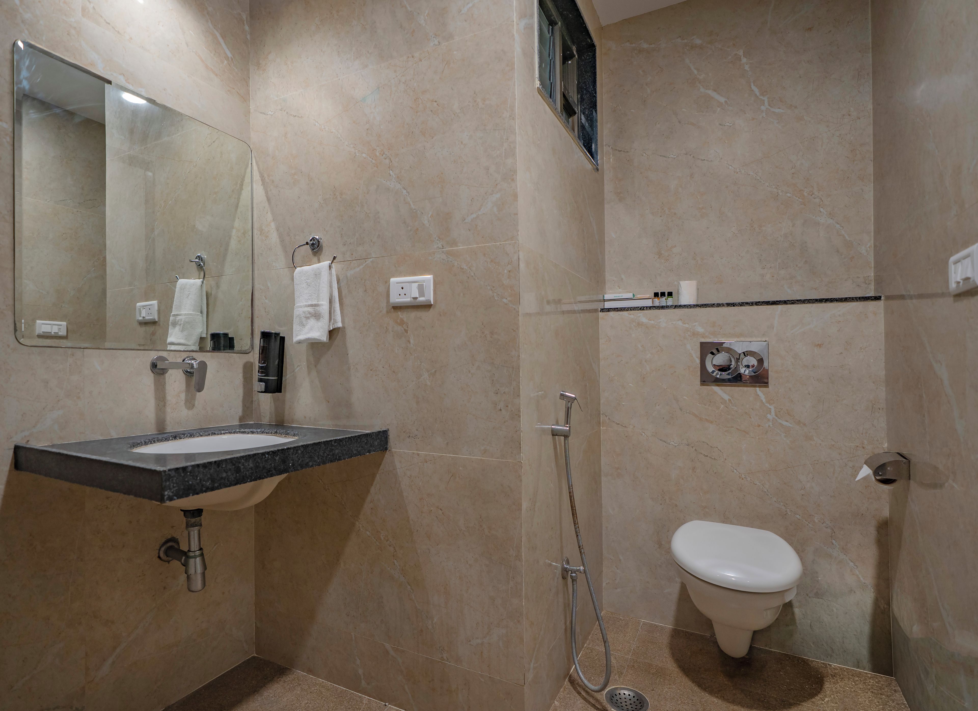 Un baño con lavamanos, espejo, toallero, ducha e inodoro.