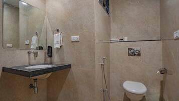 Un baño con lavamanos, espejo, toallero, ducha e inodoro.