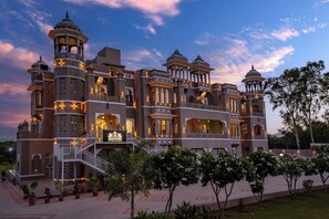 A large, multi-story building with traditional architectural elements, including domes and ornate balconies. - The Biletha Bagh (Udaipur)