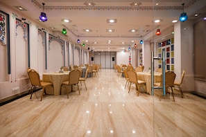 Una sala de banquet amb taules i cadires rodones, un sòl polit i llums decoratives al sostre.