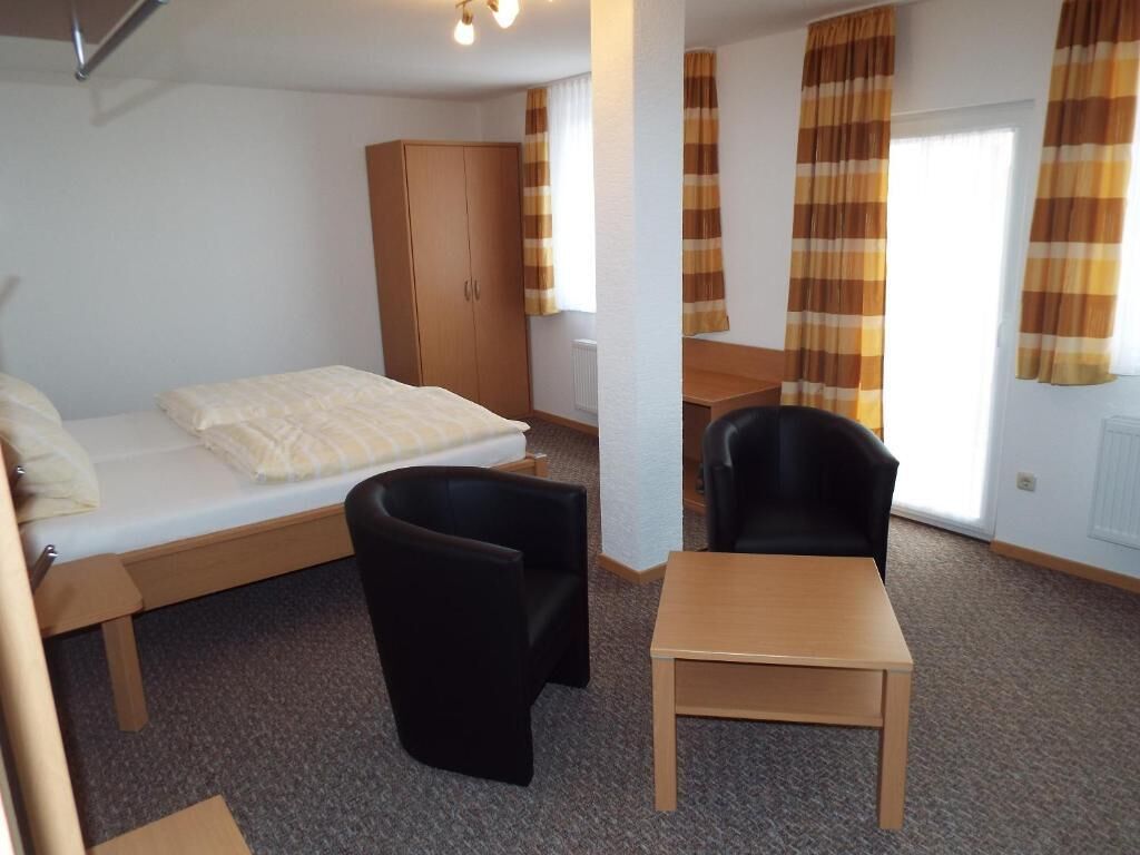 A room with a bed, a desk, a chair, and a wardrobe.