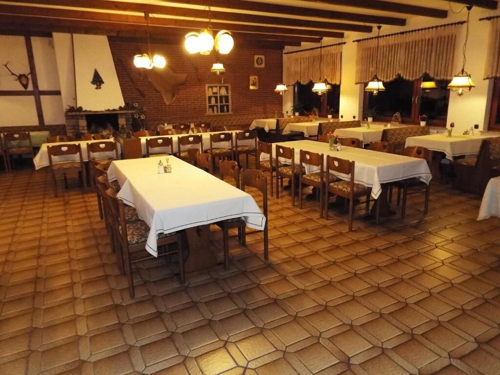 A dining area with hexagonal patterned flooring, wooden tables with white tablecloths, and hanging light fixtures.