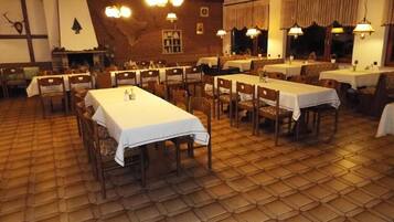 A dining area with hexagonal patterned flooring, wooden tables with white tablecloths, and hanging light fixtures.