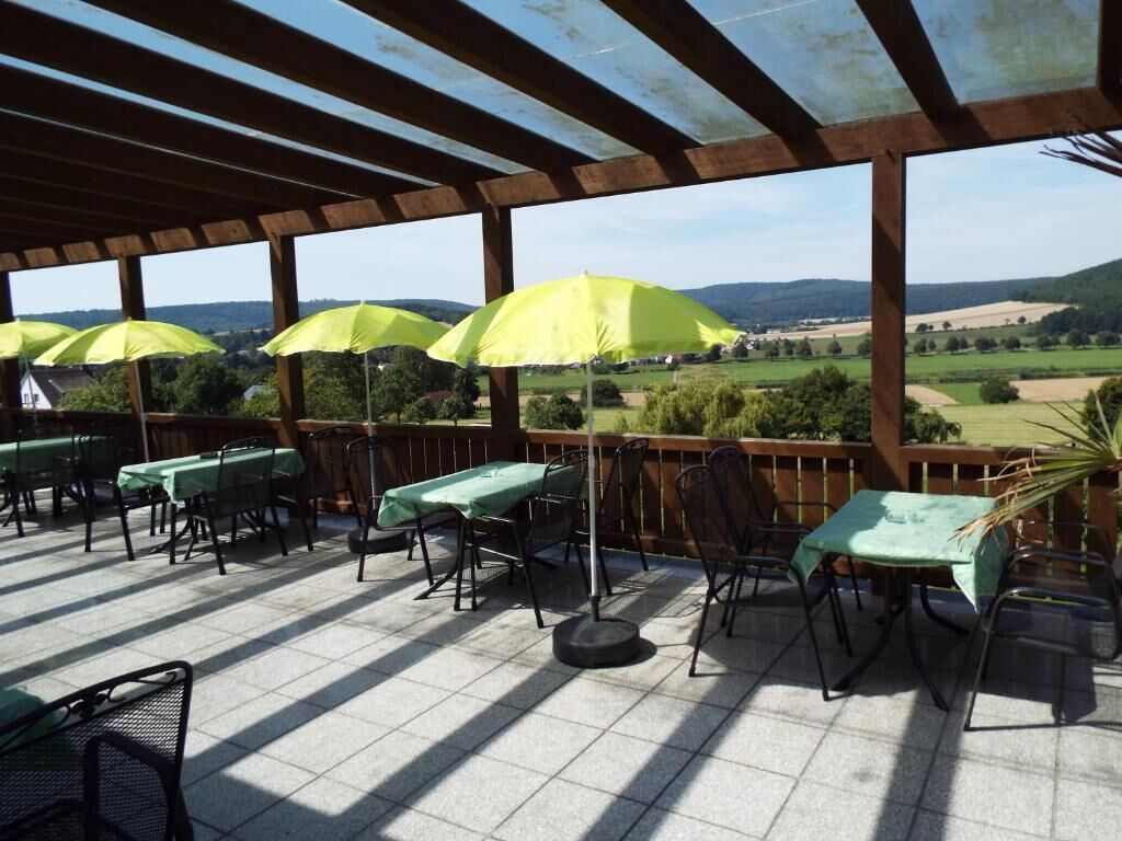 Eine Außenpatio mit Tischen, Stühlen und Sonnenschirmen, mit Blick auf die Landschaft.