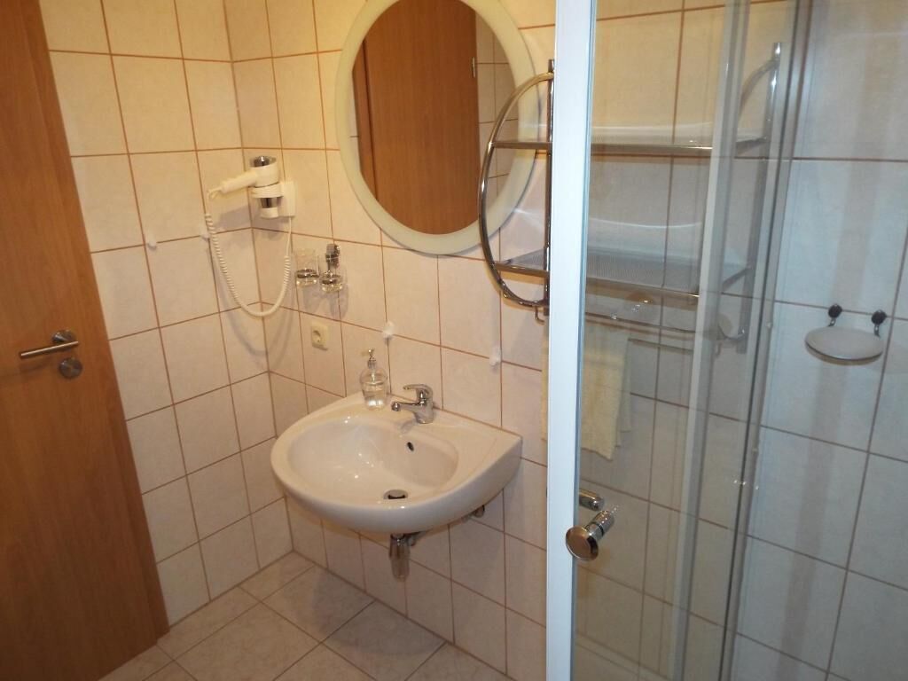 Un baño con lavamanos, espejo y ducha.