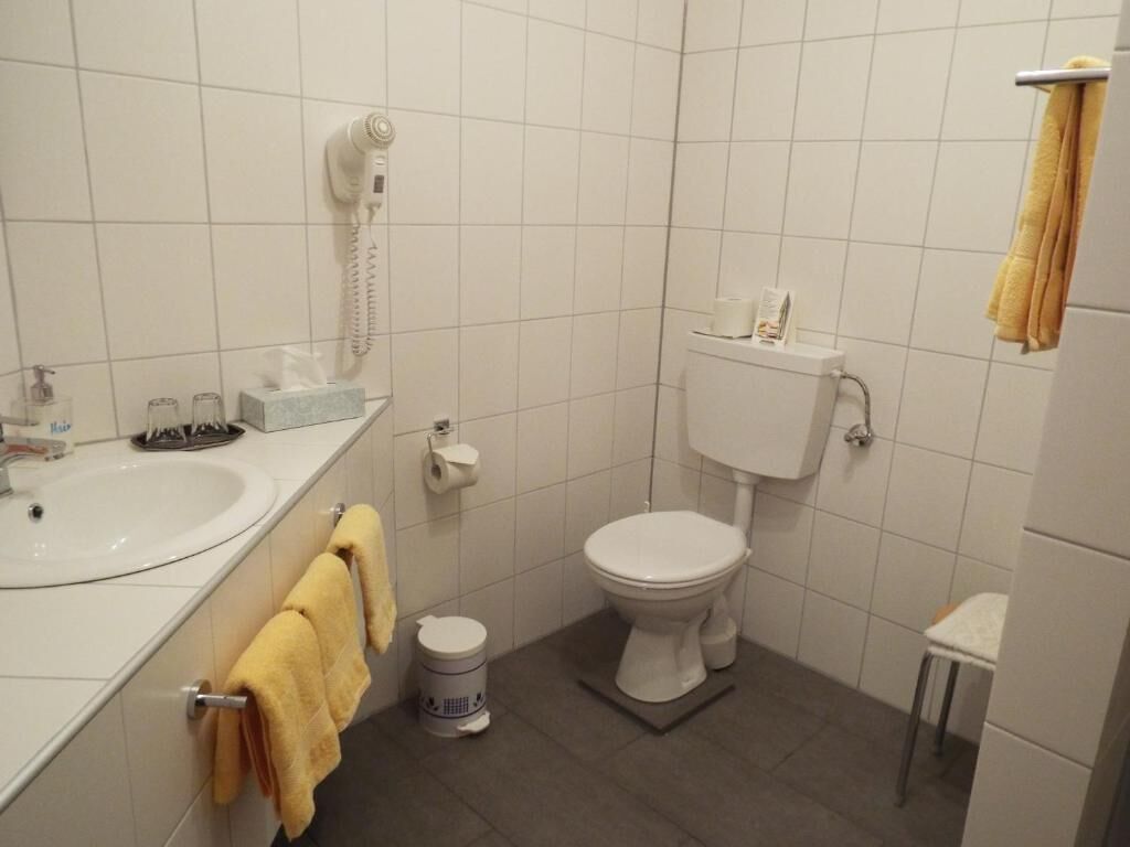 A small bathroom with a toilet, sink, and a hairdryer on the wall.