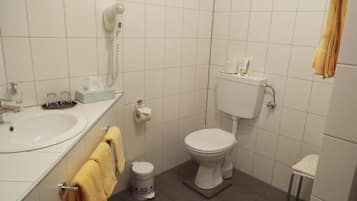 A small bathroom with a toilet, sink, and a hairdryer on the wall.