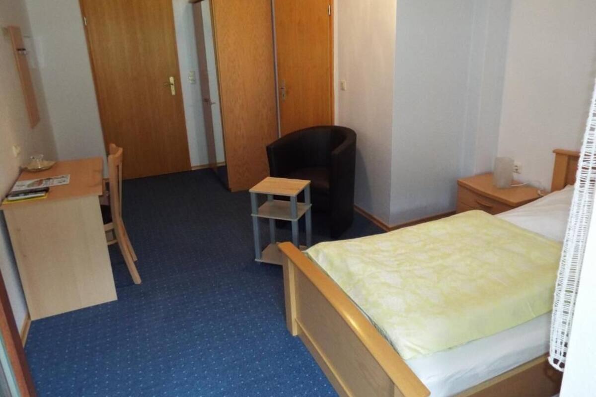 Un dormitorio con una cama, un escritorio, una silla y dos armarios.