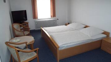 A hotel room with a bed, a television, a chair, and a small table.