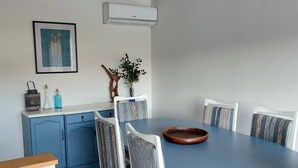 A dining area with a blue table, white chairs, and a blue cabinet. - Casa da Flor 3 (Amarante)