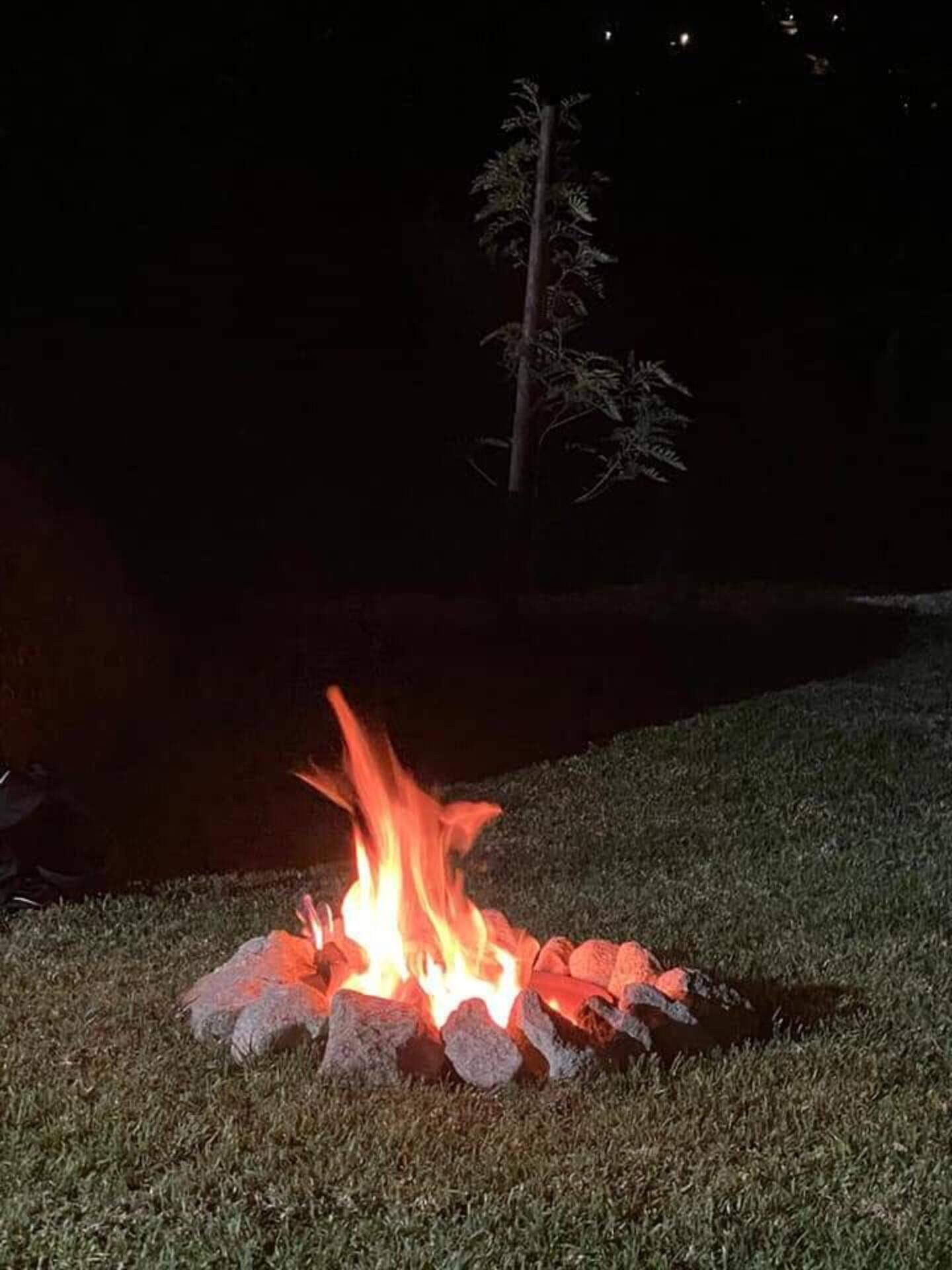 Un fuoco da campo con pietre disposte a cerchio su una zona erbosa di notte.