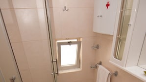 Casa de banho com cabine de chuveiro em vidro, pia branca e sanita.