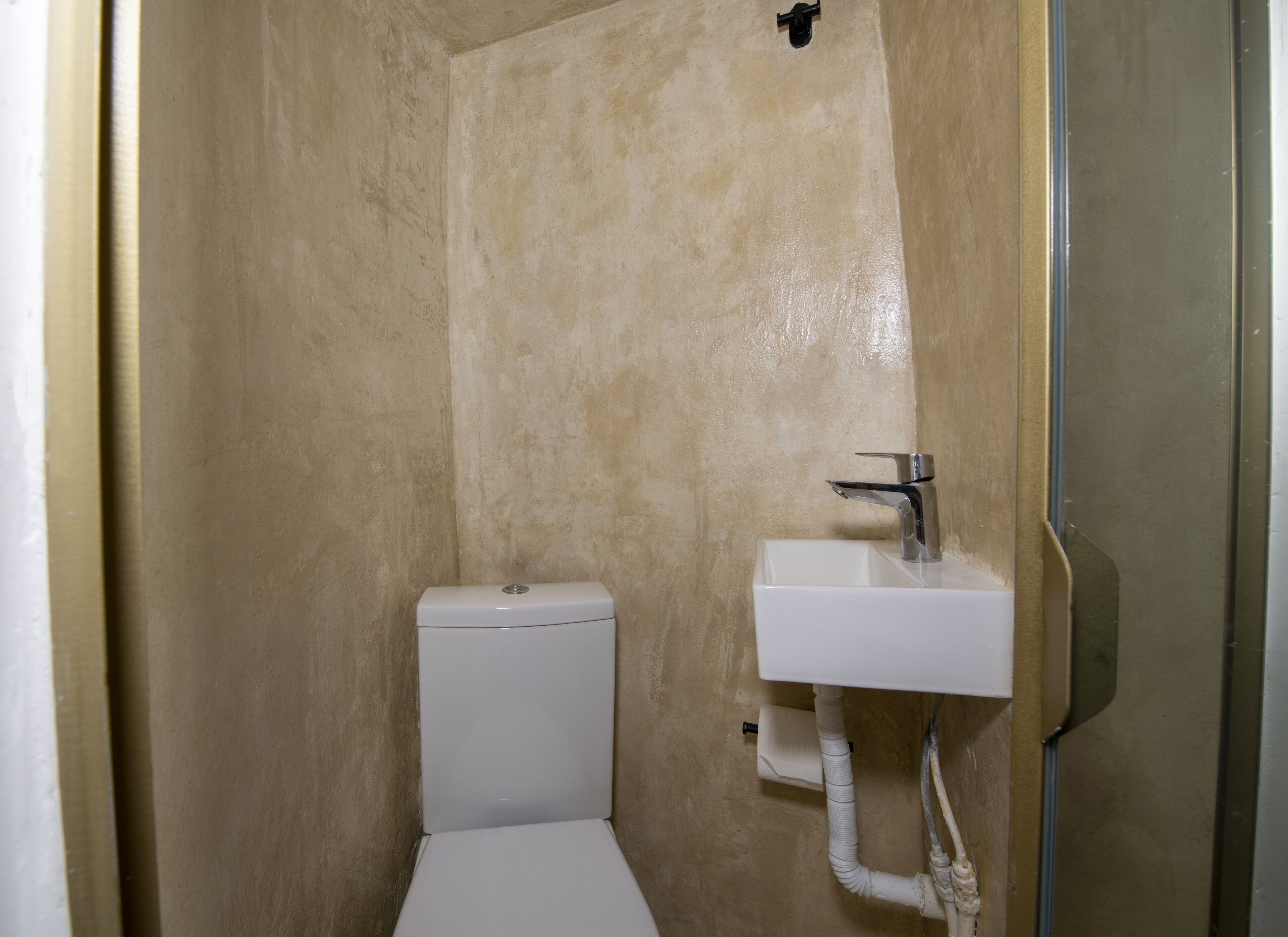 A small, enclosed bathroom with a toilet and a sink.